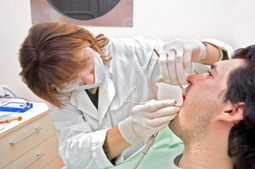 female dentist works on mans teeth