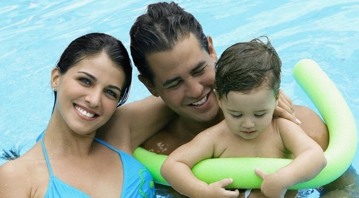 parents with their kid in a pool