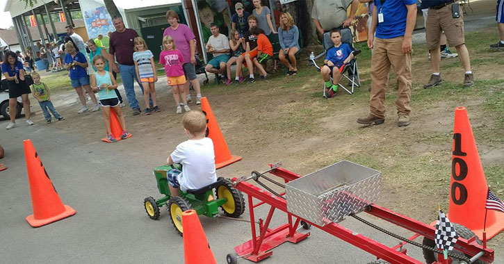 a little boy in a tractor pull contest with people watching