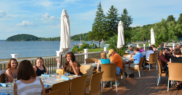 crowd of people having lunch on a patio by Saratoga Lake