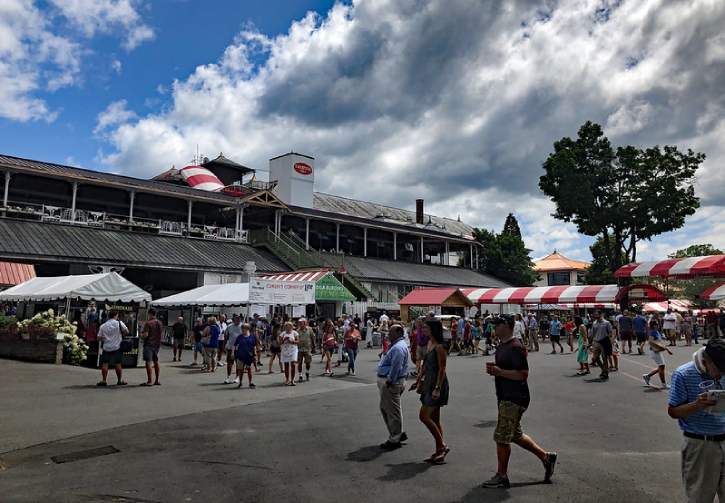 people walking around merchant tents at track