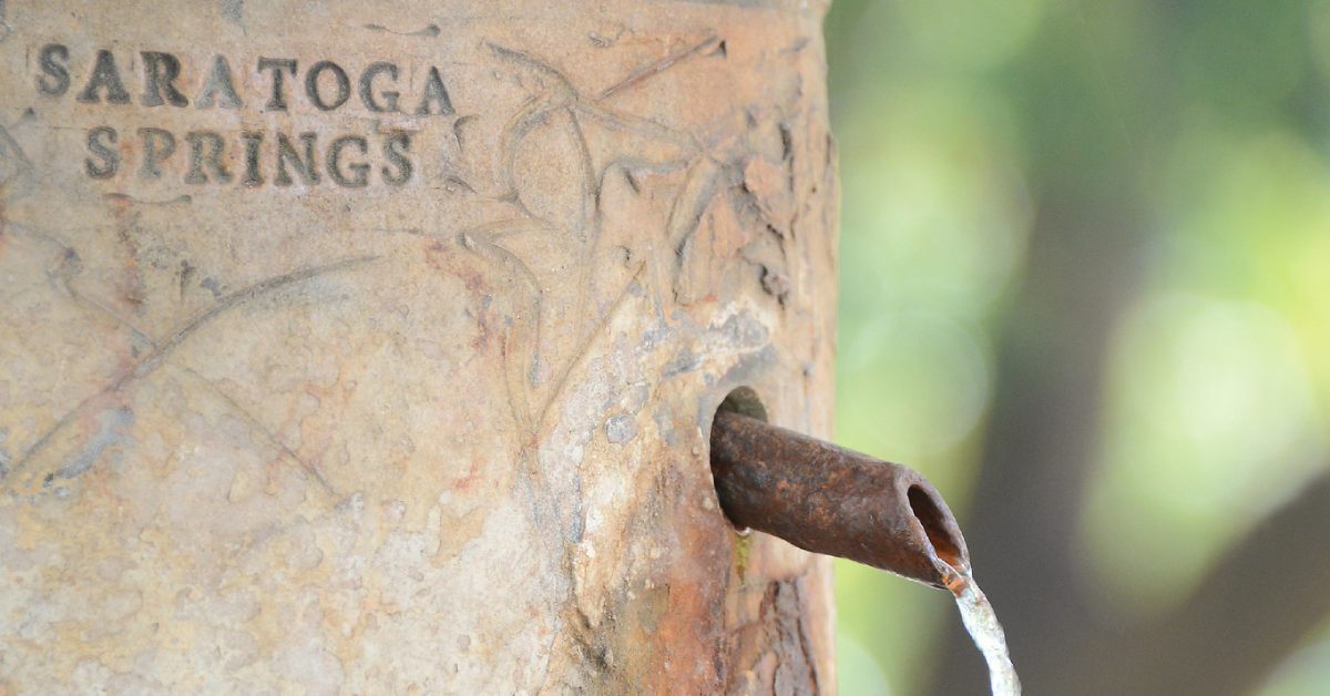 closeup shot of mineral water coming out of a spring with saratoga springs carved into it