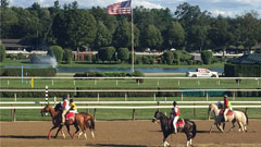 horses on the track with an American flag in the background