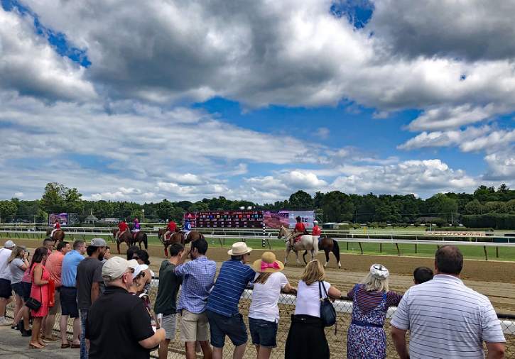 people watching horses on the track from the rail